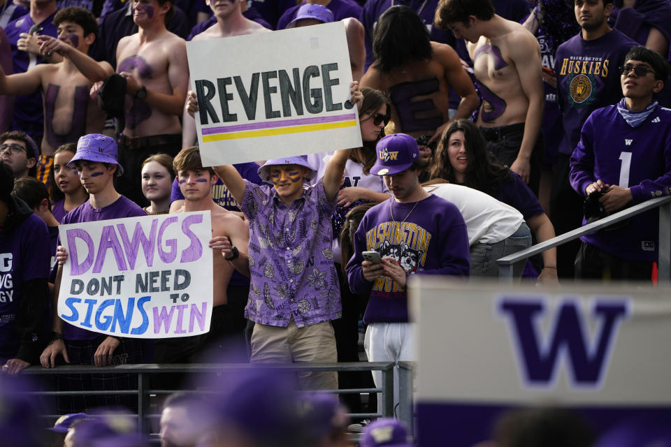 Washington fans hold signs before an NCAA college football game between Washington and Michigan, Saturday, Oct. 5, 2024, in Seattle. (AP Photo/Lindsey Wasson)