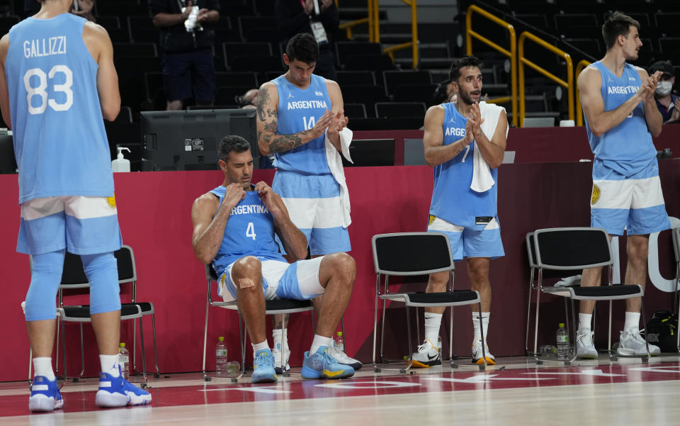 Argentina's Luis Scola (4) reacts as he receives an emotional standing ovation from his team, Australia players, and others in attendance when he was pulled from the game in the final moments of a men's basketball quarterfinal round game at the 2020 Summer Olympics, Tuesday, Aug. 3, 2021, in Saitama, Japan. (AP Photo/Eric Gay)