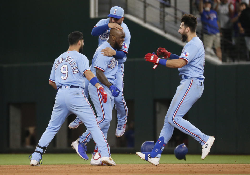Texas Rangers' Adolis Garcia, bottom center, is hugged by Jose Trevino, top center, as Isiah Kiner-Falefa, left, and Joey Gallo, right, join in after a walk-off single against the Houston Astros in the tenth inning of a baseball game in Arlington, Texas, Sunday, May 23, 2021. (AP Photo/Ray Carlin)
