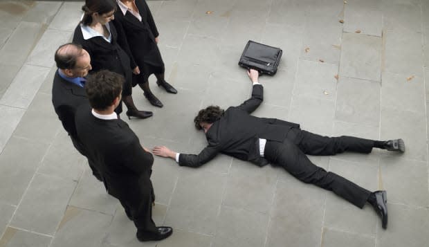 Business people looking down at man lying on pavement, elevated view