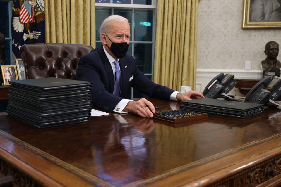 US President Joe Biden prepares to sign a series of executive orders at the Resolute Desk in the Oval Office.