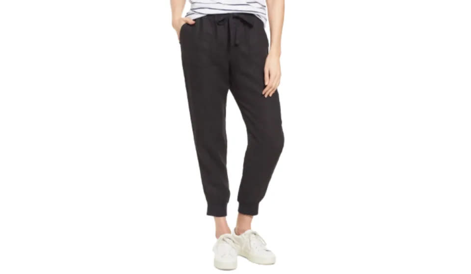 Lower half of model wearing black linen joggers with white sneakers