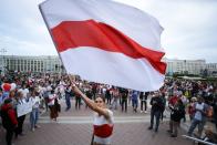 A man waves an old Belarusian national flag as Belarusian opposition supporters gather at Independence Square in Minsk, Belarus, Wednesday, Aug. 26, 2020. Protests demanding the resignation of Belarus' authoritarian President Alexander Lukashenko have entered their 18th straight day on Wednesday. (AP Photo/Sergei Grits)