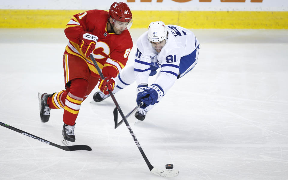 Toronto Maple Leafs' John Tavares, right, checks Calgary Flames' Dominik Simon during the third period of an NHL hockey game, Tuesday, Jan. 26, 2021 in Calgary, Alberta. (Jeff McIntosh/The Canadian Press via AP)