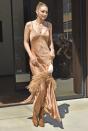 <p>In a champagne fringe slip dress, tan boots, layered gold necklaces, and a shell handbag. </p>