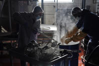 Rabbi Joseph Schwartz, left, and Ryan Eleazar use boiling water to kosherize equipment for the Hanan Products' kosher-for-passover production run Thursday, Jan. 7, 2021. in Hicksville, N.Y. At Hanan Products, which since 1946 has made primarily whipped toppings, icings and dessert fillings for the bakery industry, cleaning and production for kosher-for-Passover products begin long before the weeklong holiday that this year starts in late March. (AP Photo/Seth Wenig)