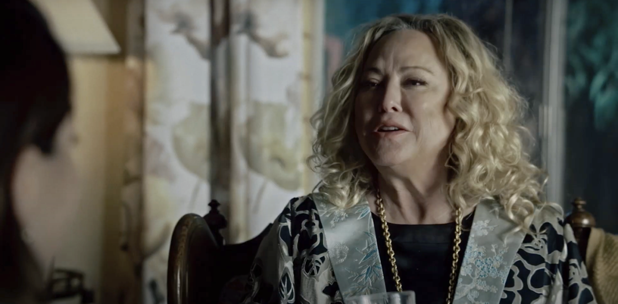 virginia madsen as mags in the portrait, a woman with curly hair talks to someone out of shot