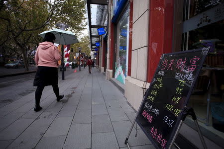 A woman walks past a board showing the length and annual yield rates of finance products, outside a shop in Shanghai, China, November 18, 2015. REUTERS/Aly Song