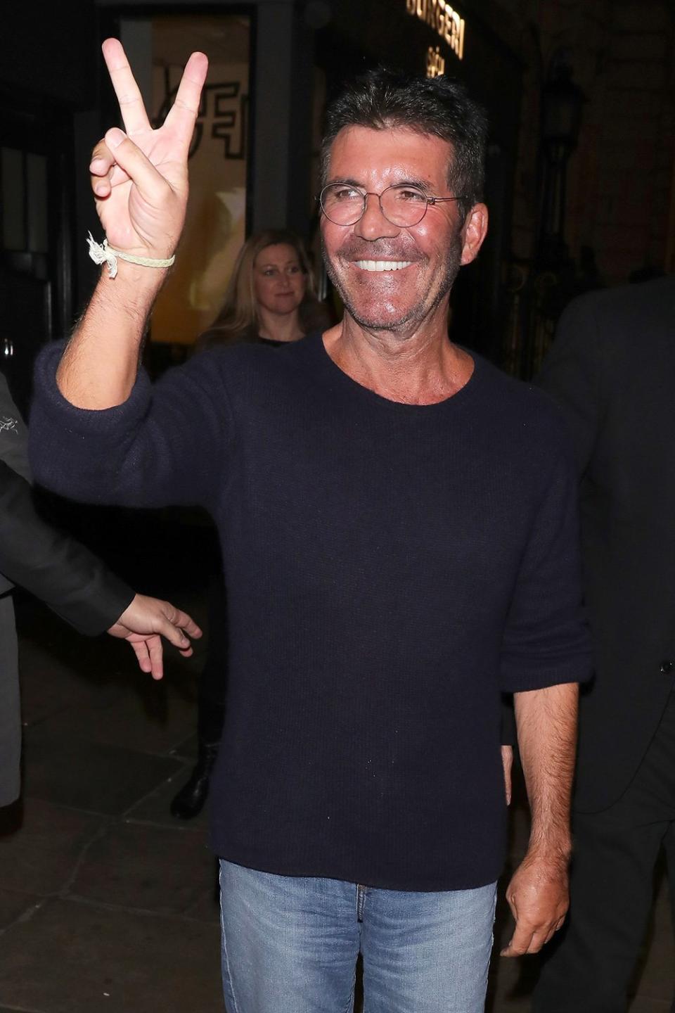 Simon Cowell greets fans as he leaves the London Palladium on Monday in England.