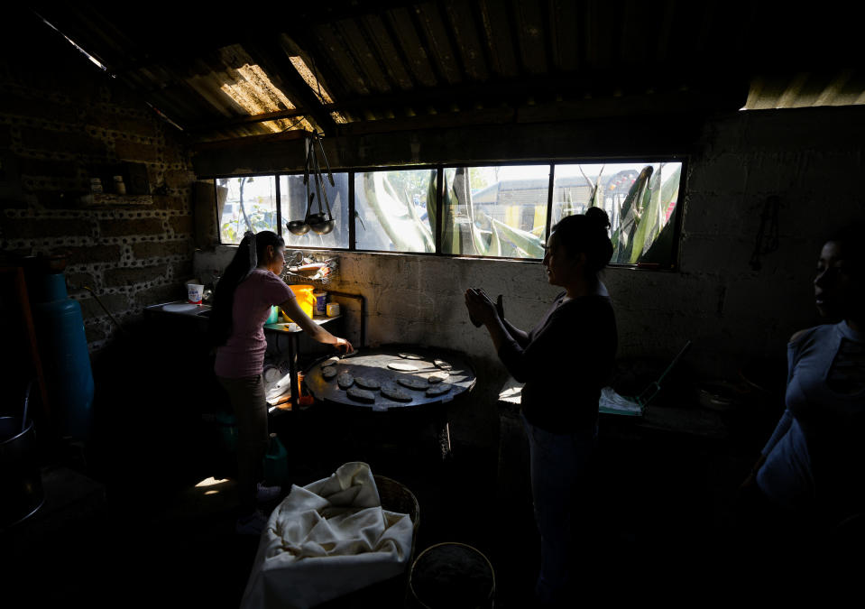 Women make tortillas made with native purple corn during a meeting of farmers, in Apizaco, Mexico, Thursday, May 18, 2023. Heirloom varieties make up far less than 1% of total domestic corn production in Mexico. But for the first time in years, some farmers are hopeful about the crop. (AP Photo/Fernando Llano)