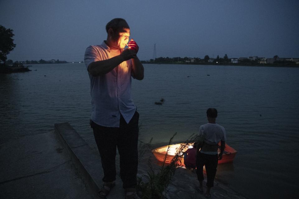 Huang Guoxin lights a cigarette near his home in Dixi village, Jiangxi province.