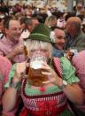 A woman wears a traditional Bavarian Dirndl dress as she drinks beer in a beer tent at the Oktoberfest 2012.
