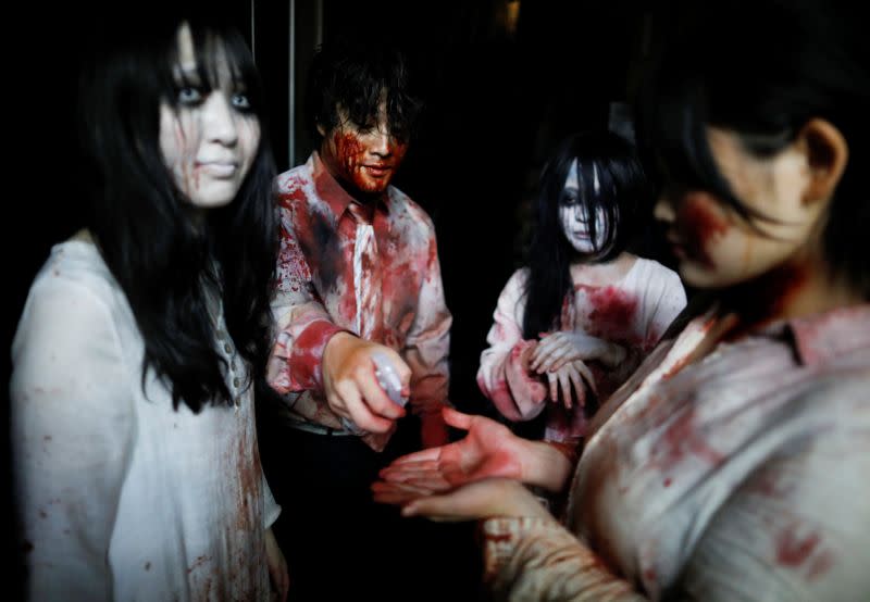 Actors dressed as zombies or ghouls disinfect their hands before their performance at a drive-in haunted house show by Kowagarasetai, for people inside a car in order to maintain social distancing amid the spread of the coronavirus disease (COVI