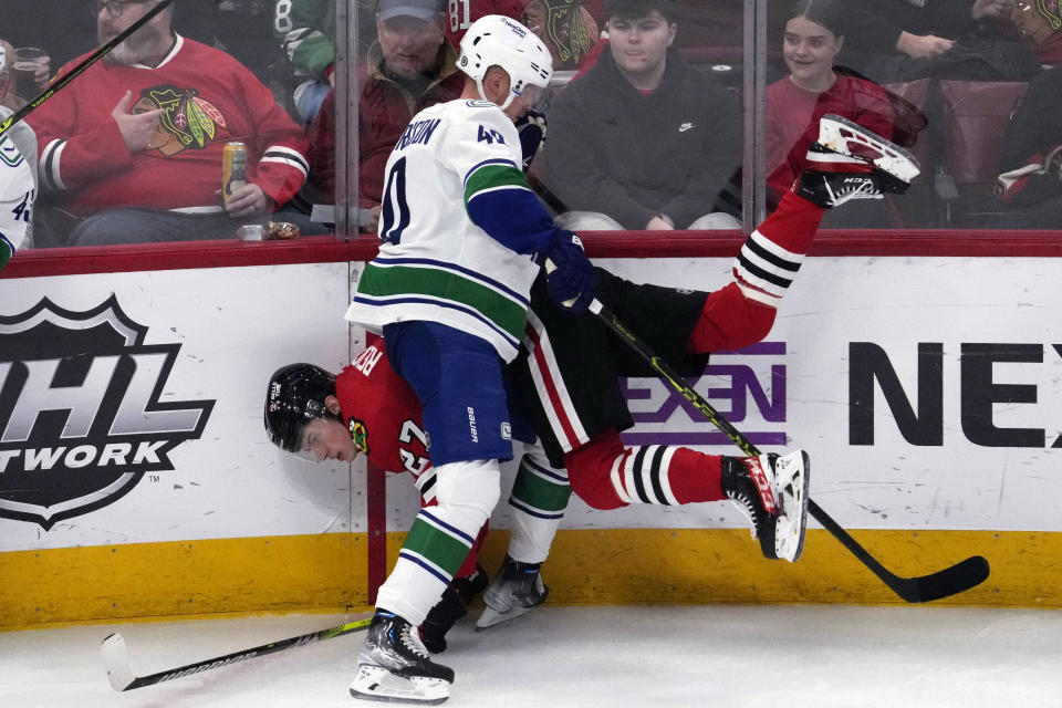 Chicago Blackhawks left wing Lukas Reichel (27) is checked by Vancouver Canucks center Elias Pettersson (40) during the third period of an NHL hockey game in Chicago, Sunday, March 26, 2023. (AP Photo/Nam Y. Huh)