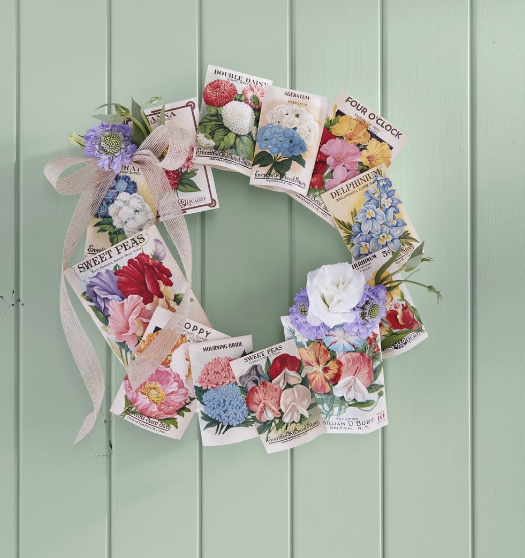 a wreath made from vintage seed packets hung on a light green background