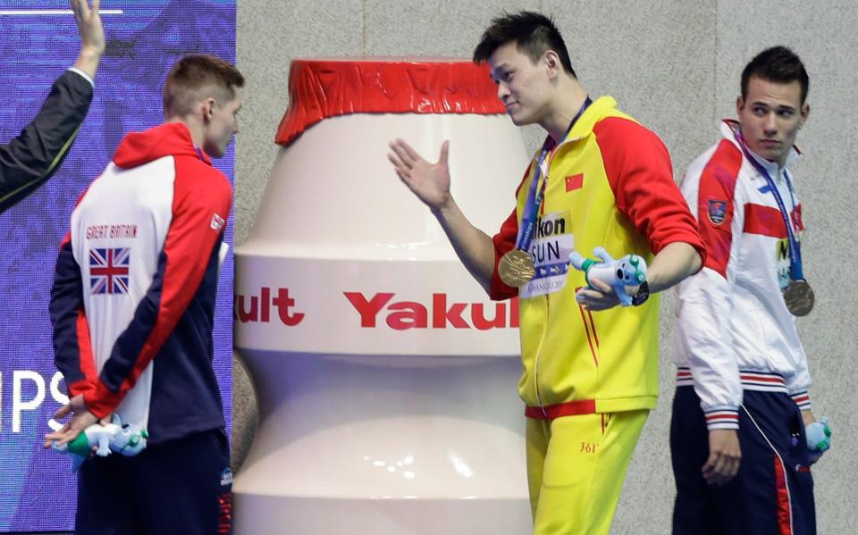 China's Sun Yang, centre, gestures to Britain's bronze medalists Duncan Scott, left, following the medal ceremony in the men's 200m freestyle final at the World Swimming Championships in Gwangju, South Korea. Chinese swimmer Sun Yang has been banned for eight years for breaking anti-doping rules and will miss the 2020 Tokyo Olympics - AP Photo/Mark Schiefelbein