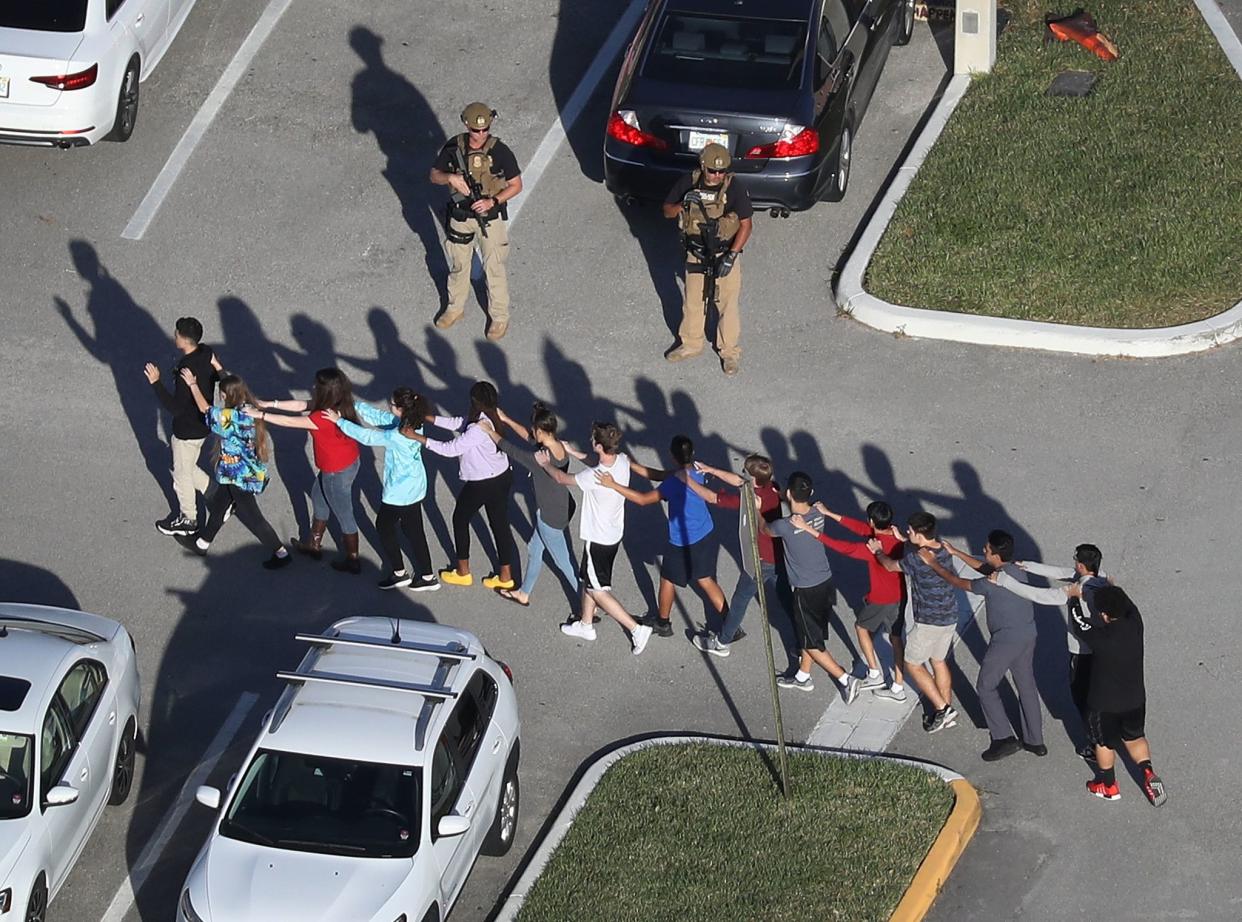 People are brought out of Marjory Stoneman Douglas High School after the Feb. 14, 2018, Parkland, Fla., shooting.