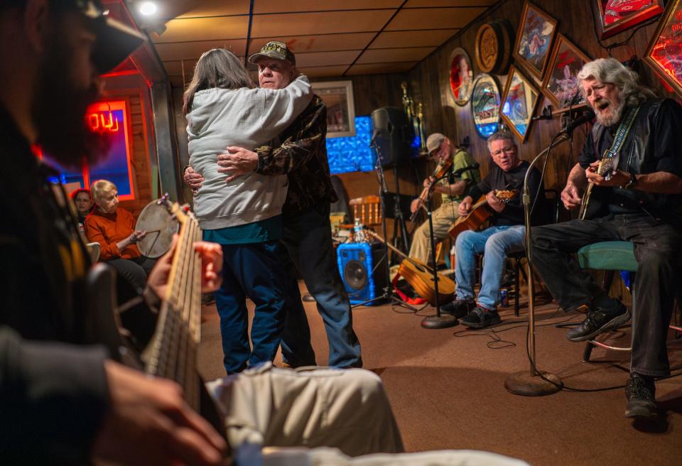 Bob Popour, of Manistique, shares a dance with Audrey Byars, of Manistique, as Tom Mercier, right, of Manistique, sings with other local musicians playing music during a weekly jam band session where locals bring their instruments to play and sing along at Roy's Place bar in Manistique on Tuesday, March 26, 2024.