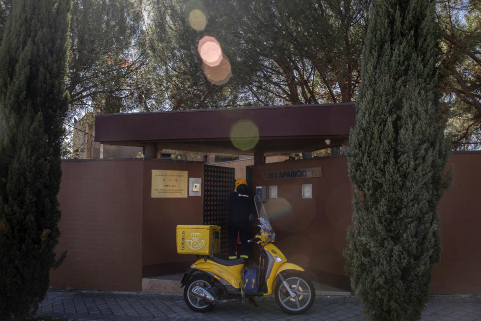 In this Wednesday, March 13, 2019 photo, a Spanish postman talks to a member of North Korea's embassy, not seen, in Madrid, Spain. A Spanish court is accusing an American, Mexican and South Korean part of a 10-strong group that led an attack on the North Korean Embassy in February, saying the FBI was offered stolen data. National Court judge Jose de la Mata on Tuesday, March 26 lifted a secrecy order, announcing it had found evidence of various crimes, including trespassing, injuries, threats and burglary committed by "a criminal organization." (AP Photo/Bernat Armangue)