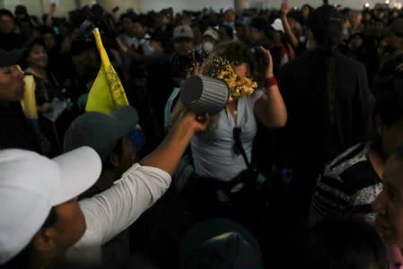 A woman throws food to a member of local medial in the aftermath of the last days' protests, after the government of Ecuadorian President Lenin Moreno agreed to repeal a decree that ended fuel subsidies, in Quito