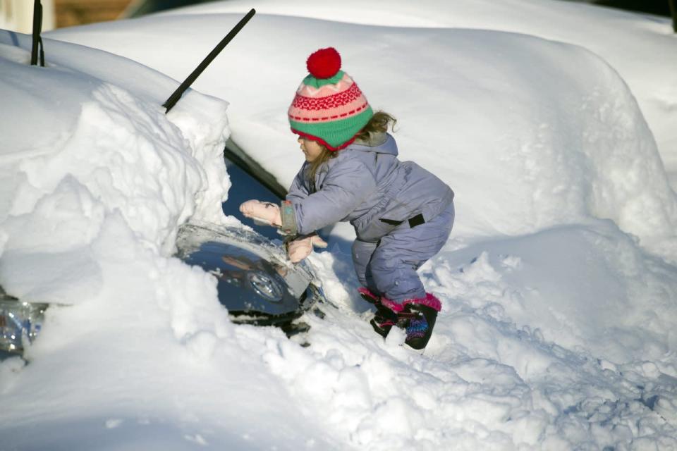 Tess Jorgensson, 3, helps her father dig their car out of snow in Alexandria, Va., Sunday, Jan. 24, 2016. [AP Photo/Cliff Owen]