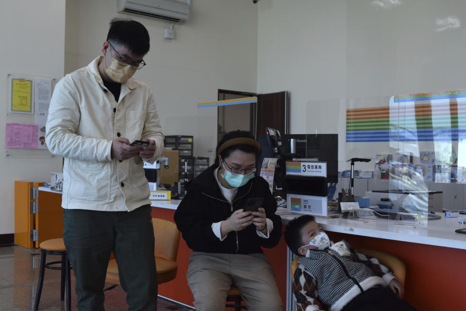 Chiu Sih-chi and his wife take the opportunity to use the wifi in the Chunghwa Telecom office as their son rests on a chair in Nangan,, part of Matsu Islands, Taiwan on Sunday, March 5, 2023. Chiu said the recent internet outage made it difficult to book a hospital appointment for his toddler. Thousands of residents of Taiwan's outlying islands near the Chinese coast have been without the internet for the past month. Chunghwa Telecom, Taiwan's largest service provider and owner of the two submarines cables that serve Matsu islands, says Chinese vessels cut them. (AP Photo/Huizhong Wu)