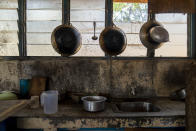 Pots and pans hang in the kitchen of workers' living quarters in a palm oil plantation run by the government-owned Felda in Malaysia in early 2020. Jum, a former worker who escaped from this same plantation, said the company confiscated, and later lost his Indonesian passport, leaving him vulnerable to arrest and forcing him to hide in the jungle. (AP Photo/Ore Huiying)