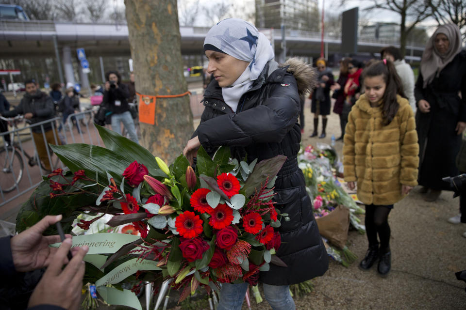 Women representing Utrecht's Muslim community lay a wreath at a makeshift memorial for the victims of a shooting incident in a tram in Utrecht, Netherlands, Tuesday, March 19, 2019. A gunman killed three people and wounded others on a tram in the central Dutch city of Utrecht Monday March 18, 2019. (AP Photo/Peter Dejong)