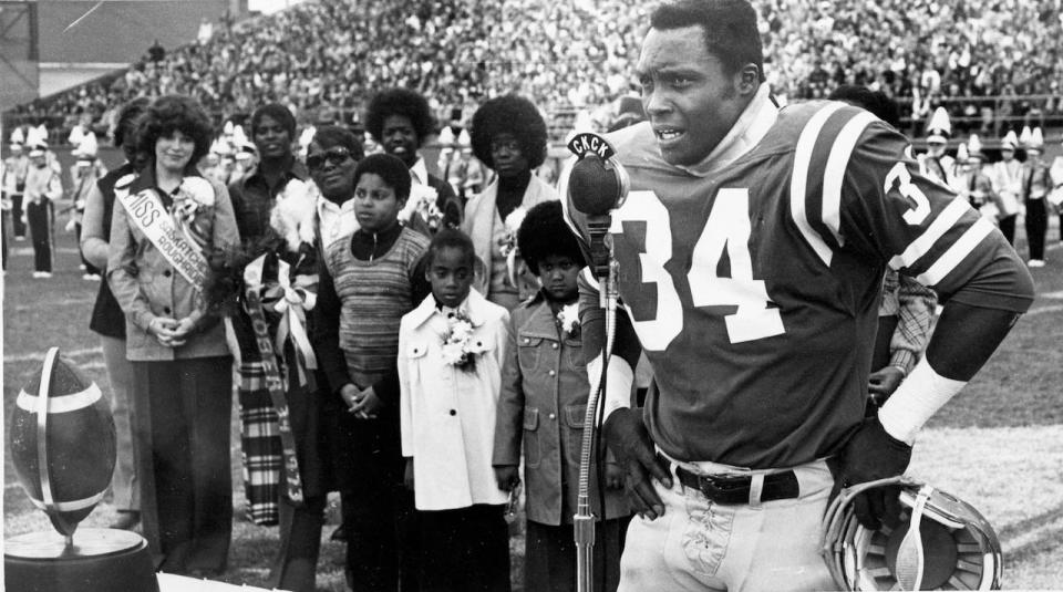 Saskatchewan Roughrider fullback George Reed speaks at a cermony held in his honor as members of his family watch, Oct 8, 1973.  At left is the football, now mounted as a trophy, which he used in August game to set a professional football career rushing record. (CP PHOTO/Stf)  