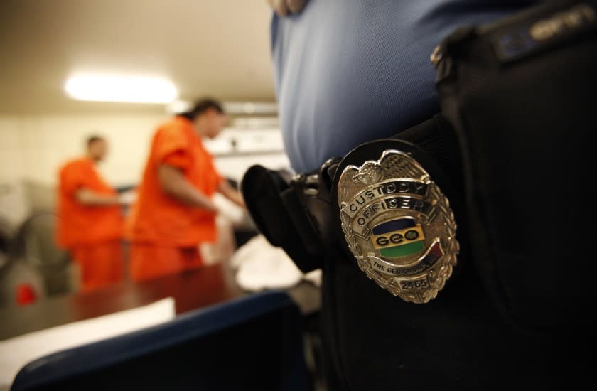 A guard watches as inmates fold clothes at the new immigrant detention center in Bakersfield.