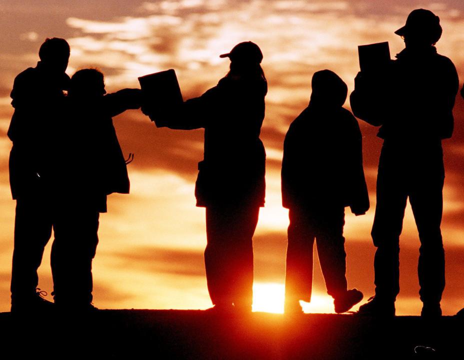 Early risers catch a glimpse of a  solar eclipse on the rocks at Peggy's Cove, Nova Scotia on Wednesday Aug. 11, 1999 using an improvised pinhole camera to safely view the phenomenon. (CP PHOTO/Andrew Vaughan)