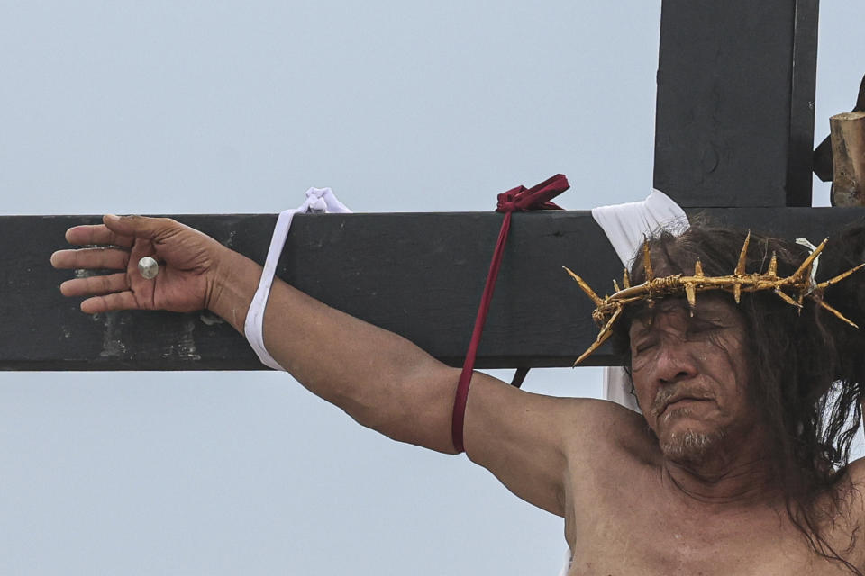 Ruben Enaje remains on the cross during a reenactment of Jesus Christ's sufferings as part of Good Friday rituals in San Pedro Cutud, north of Manila, Philippines, Friday, March 29, 2024. The Filipino villager was nailed to a wooden cross for the 35th time to reenact Jesus Christ’s suffering in a brutal Good Friday tradition he said he would devote to pray for peace in Ukraine, Gaza and the disputed South China Sea. (AP Photo/Gerard V. Carreon)