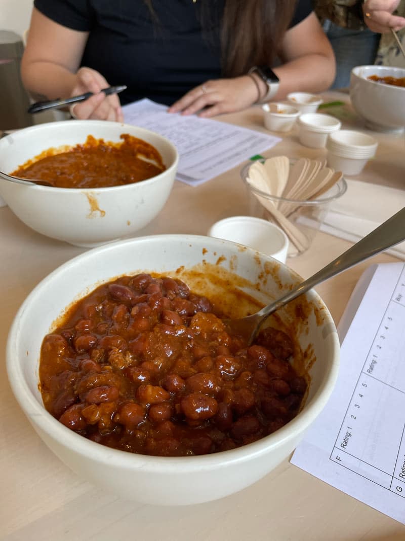 Taste testers rating bowls of canned chili on dining table.