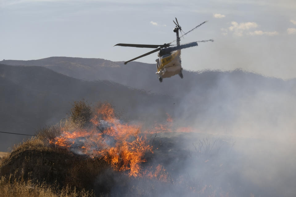 A helicopter prepares to drop water on a wildfire in Castaic, Calif. on Wednesday, Aug. 31, 2022. (AP Photo/Ringo H.W. Chiu)