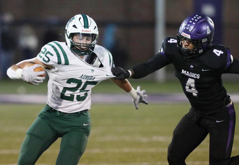 Aurora's Enzo Catania runs for yardage as Barberton's Jomyco Davis grabs on to his jersey in the first half Friday at Barberton High School.