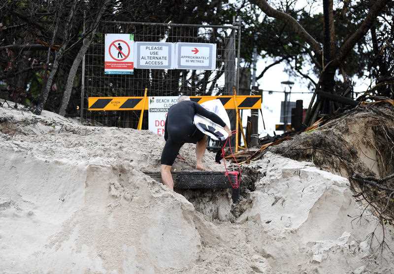 A surfer climbs up an erosion-damaged beach access at Byron Bay, NSW.