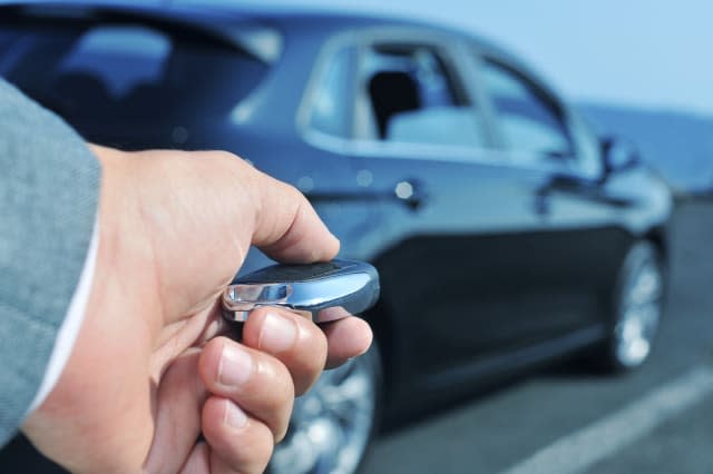 detail of a man in suit opening his car with the control remote key