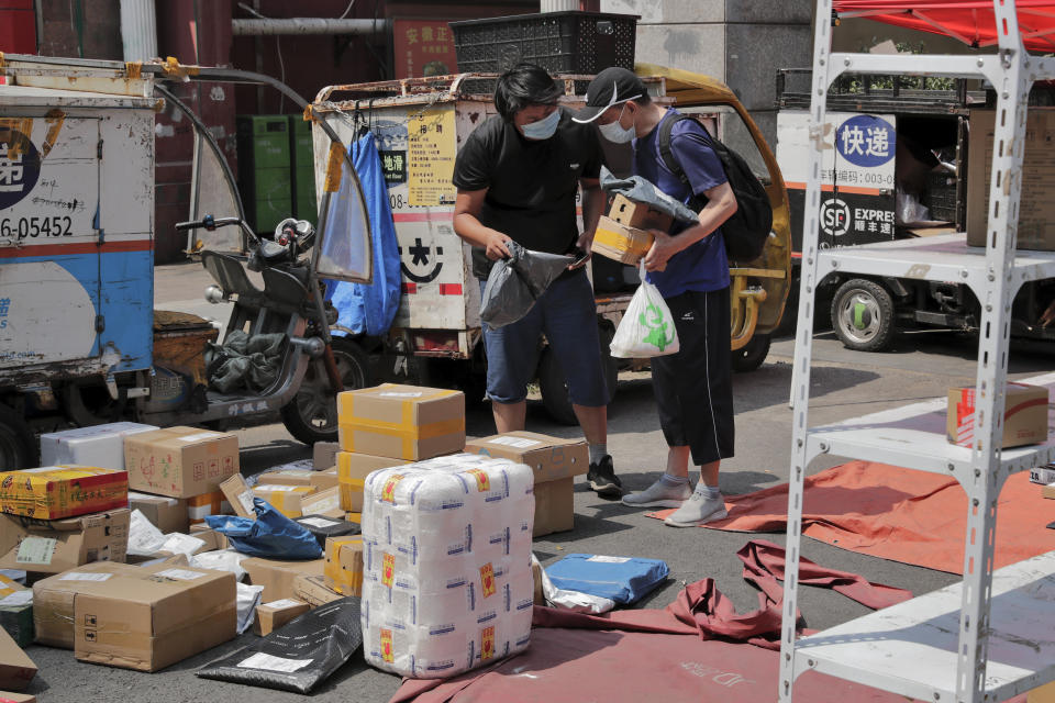 A delivery worker wearing a protective face mask to help curb the spread of the new coronavirus sorts out parcels for his customer at a collection point outside an apartment in Beijing, Sunday, June 21, 2020. According to state media reports, nearly one hundred thousand delivery workers have to accept the nucleic acid testing, a countermeasure to prevent the spread of the virus in the capital city. (AP Photo/Andy Wong)