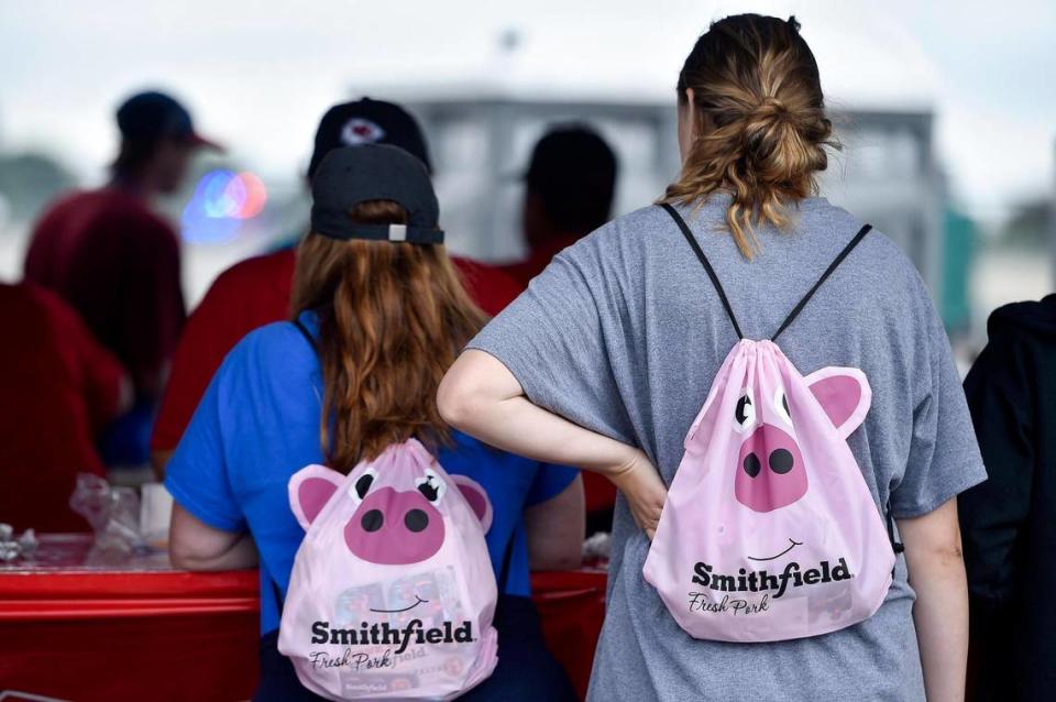 Kaylee Larson, right, and her mother Lori Larson of Olathe wear promotional packs from Smithfield while ordering from a vendor. The three-day Kansas City BBQ Festival in the parking lot of the GEHA Field at Arrowhead Stadium concluded Sunday, July 11, 2021.