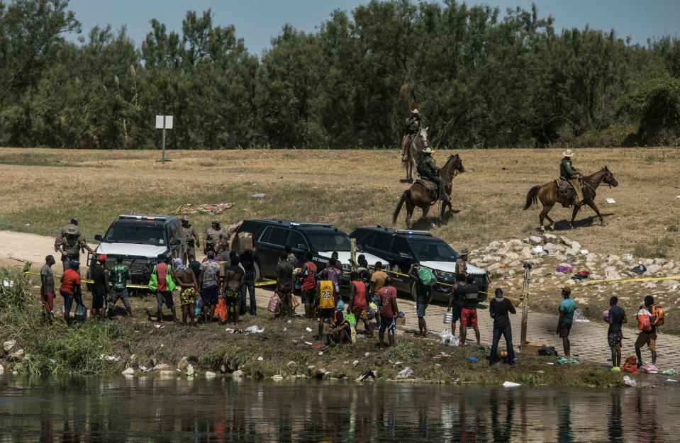 U.S. border patrol officers contain a group of migrants on the shore of the Rio Grande after they crossed from Ciudad Acuña, Mexico, into Del Rio, Texas, Sunday, Sept. 19, 2021. Thousands of Haitian migrants have been arriving to Del Rio, Texas, as authorities attempt to close the border to stop the flow of migrants. (AP Photo/Felix Marquez)