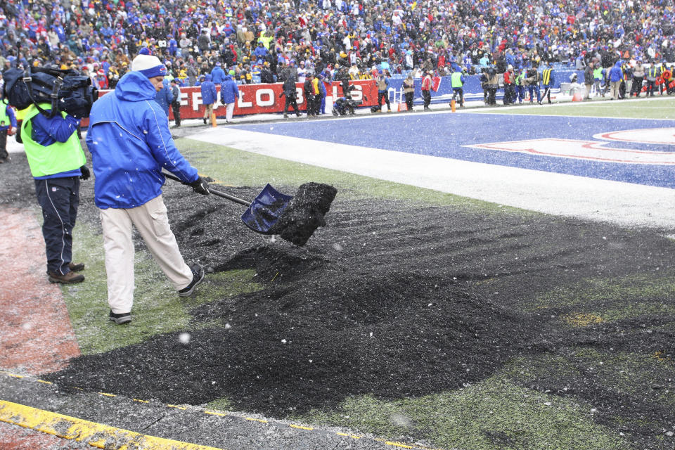 FILE - A crew member shovels a mound of turf rubber pellets swept up while cleaning snow off the field during halftime of an NFL football game between the Buffalo Bills and the Pittsburgh Steelers, Dec. 11, 2016, in Orchard Park, N.Y. (AP Photo/Bill Wippert, File)