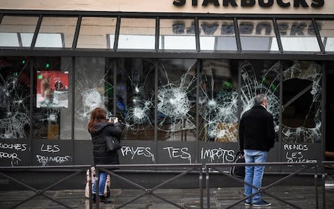 Members of the public view graffiti and broken a window of a Starbucks at Gare Saint Lizare following a fourth week of protests - Credit: Getty