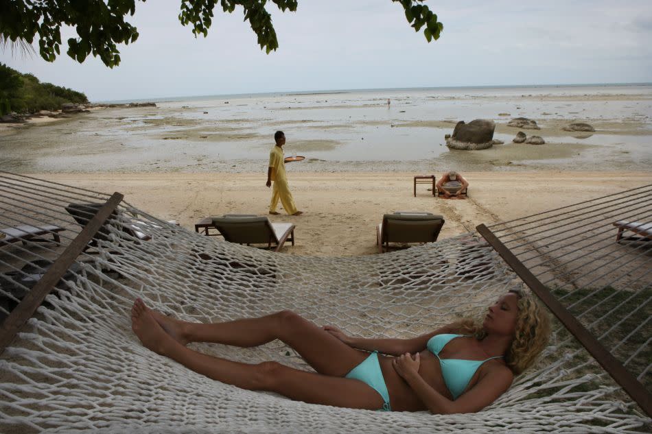 A woman rests on a hammock at the beach at the Kamalaya Wellness Sanctuary in Koh Samui, Thailand.