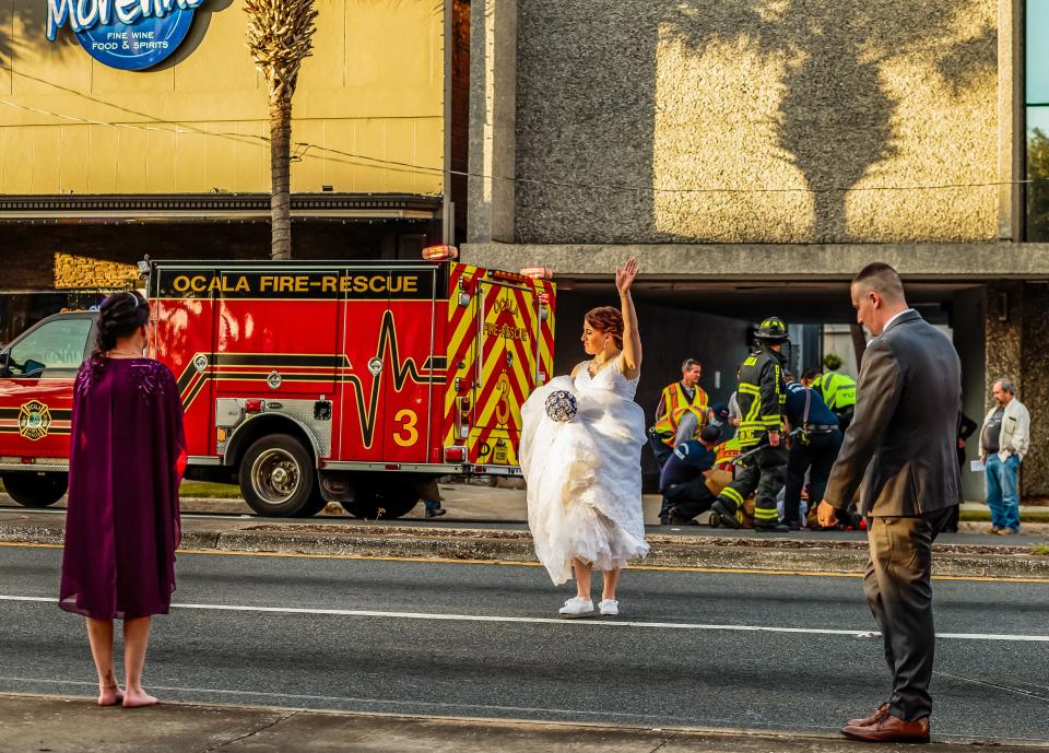 Marion County Sheriff's Corrections Officer Taylor Rafferty, center, directs traffic with her bouquet in hand as her future husband MCSO Deputy Christopher Rafferty, right, responded to a vehicle verses pedestrian accident while having their pictures take on the Ocala downtown square,  December 12, 2020 in Ocala, FL. "I was using my bouquet to direct traffic," Taylor said while laughing Friday April 2, 2021.  [Wendy McCarthy Special to the Ocala Star Banner]2020