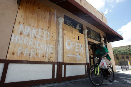 A man rides a bike past a bar with boarded up windows ahead for the arrival of Hurricane Irma in Tampa, Florida, U.S., September 9, 2017. REUTERS/Chris Wattie