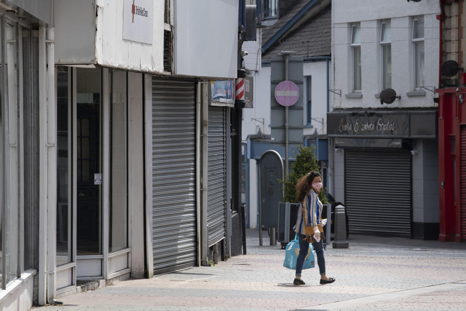 MERTHYR TYDFIL, UNITED KINGDOM - MAY 18: A woman wears a face mask and surgical gloves while carrying a bag and walking passed closed small businesses on High Street on May 18, 2020 in Merthyr Tydfil, United Kingdom. The British government has started easing the lockdown it imposed two months ago to curb the spread of Covid-19, abandoning its 'stay at home' slogan in favour of a message to 'be alert', but UK countries have varied in their approaches to relaxing quarantine measures. (Photo by Matthew Horwood/Getty Images)