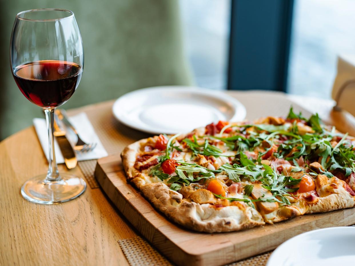 glass of red wine and an italian pizza on a table