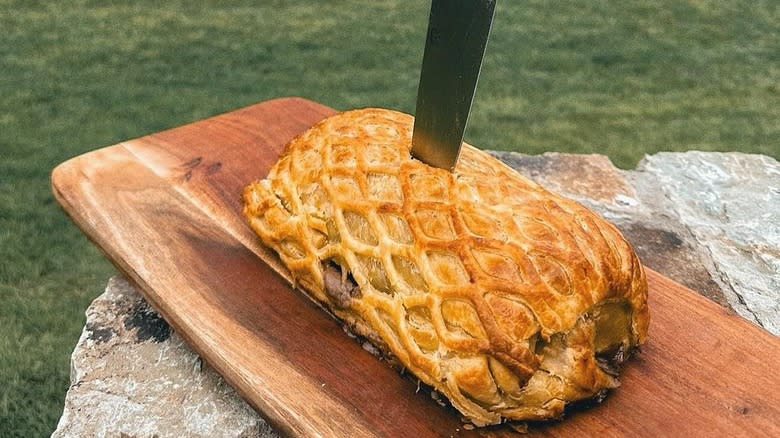 Beef wellington on wooden cutting board outside