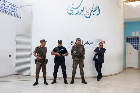 Police officers and army soldiers stand guard at a polling station in Tunis