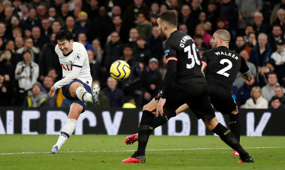 Tottenham Hotspur's Son Heung-min shoots as Manchester City's Nicolas Otamendi and Kyle Walker attempt to block.